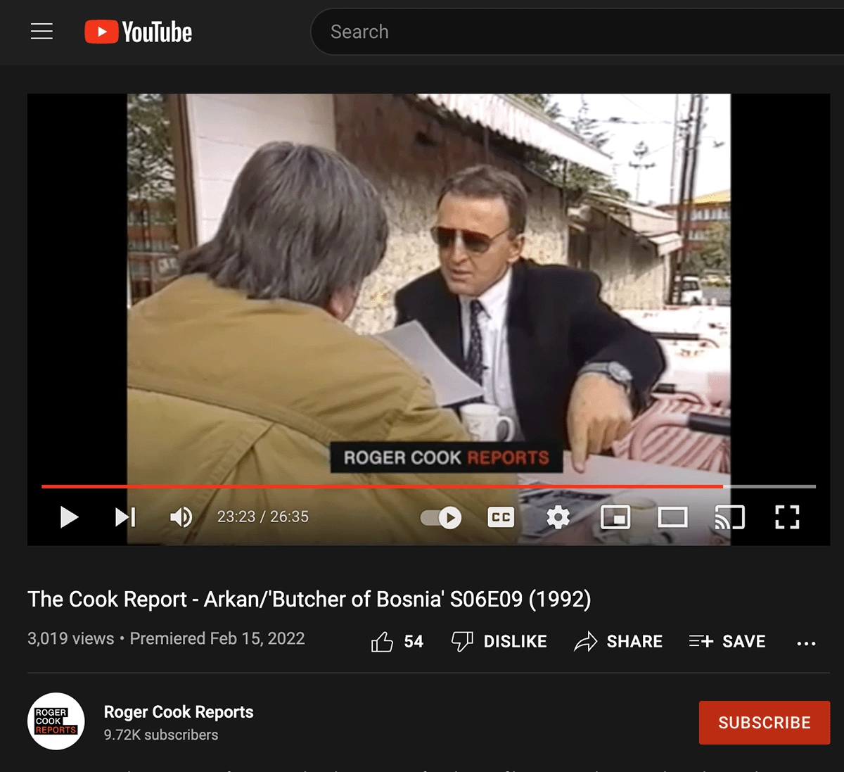 Arkan during a 1992 interview on <em><a href='https://www.youtube.com/watch?v=QIveuAV7K-A' target='_blank'>Roger Cook Reports</a></em>, pointing at photographs Haviv took in Bijeljina.
