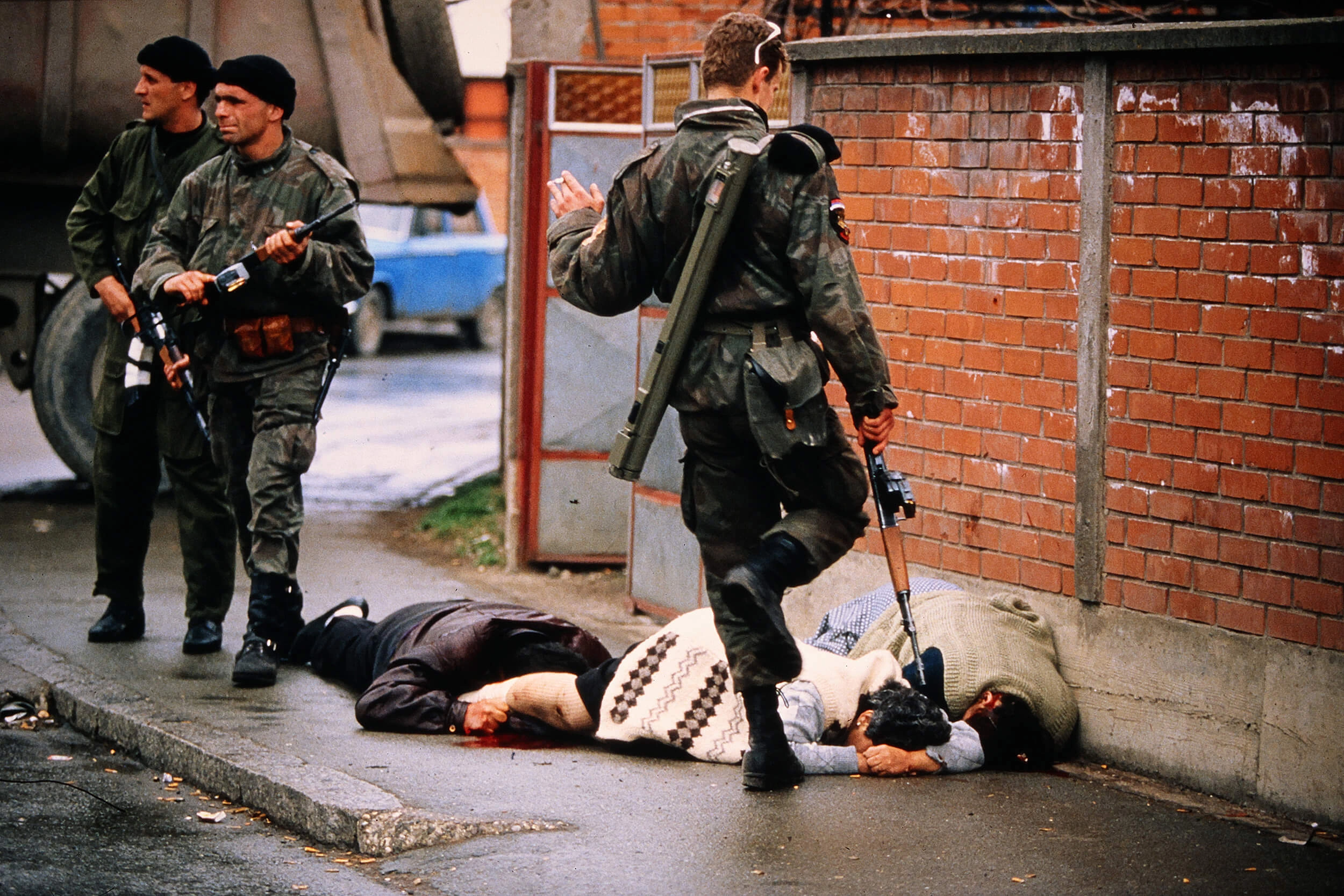 A member of Arkan's Tigers swings his boot towards the body of a civilian woman, Tifa Šabanović, in Bijeljina on April 2, 1992.