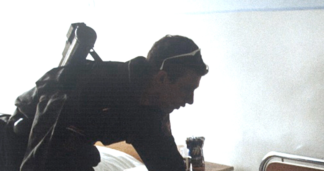 A member of Arkan's Tigers, who appears similar to more recent photos taken of Srđan Golubović, leans over a hospital bed in Bijeljina on April 2, 1992.